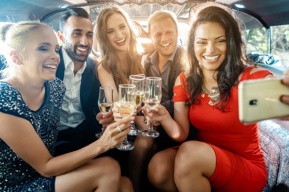 Group in limo with champagne and smart phone